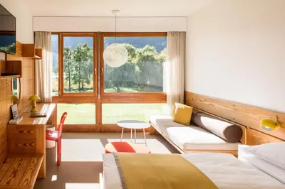 a bedroom with a bed and a couch and a window at Seehotel Ambach in Caldaro