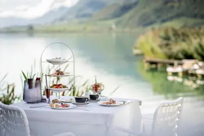 a table with plates of food and a view of a lake at Seehotel Ambach in Caldaro