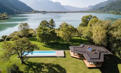 an aerial view of a house next to a lake at Seehotel Ambach in Caldaro