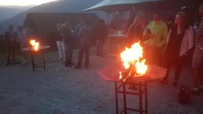 a group of people standing around fires in a field at Arche Hof Bichler in Gais