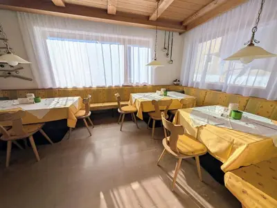 a restaurant with wooden tables and chairs and windows at Pension Atlantic in Badia