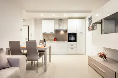 a kitchen with white cabinets and a table and chairs at Fior Apartments in Merano