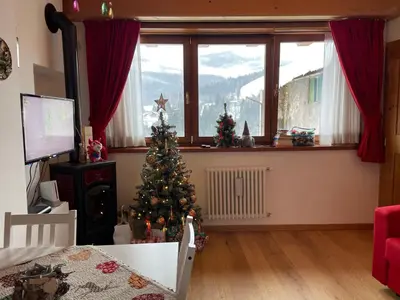 a living room with a christmas tree in front of a window at Casa Romeo in San Vito di Cadore
