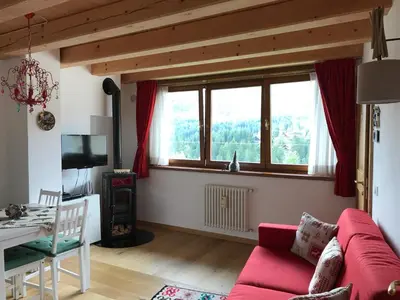 a living room with a red couch and a table at Casa Romeo in San Vito di Cadore