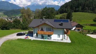 a house with a solar roof on a green field at Ferienwohnungen Schlosshäusl in San Lorenzo di Sebato