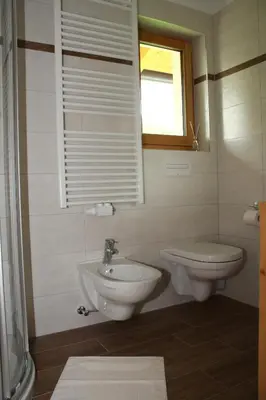 a bathroom with a sink and a toilet and a window at Ferienwohnungen Schlosshäusl in San Lorenzo di Sebato