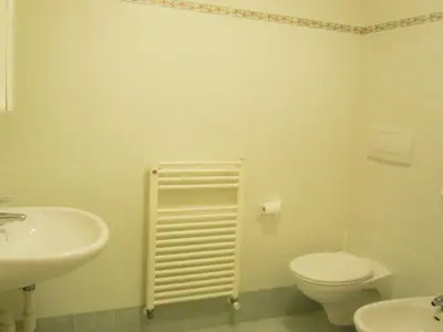 a white bathroom with a toilet and a sink at Cesa Stefi in Canazei
