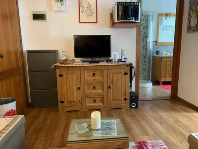 a living room with a television on a wooden cabinet at Appartamento Esprit Des Alpes in Canazei