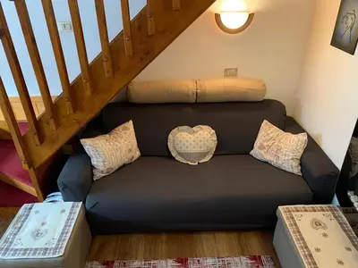 a couch with pillows sitting under a staircase at Appartamento Esprit Des Alpes in Canazei