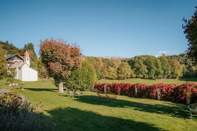 a park with chairs in the grass and flowers at Villa Maier B&B & Apartments in Soprabolzano