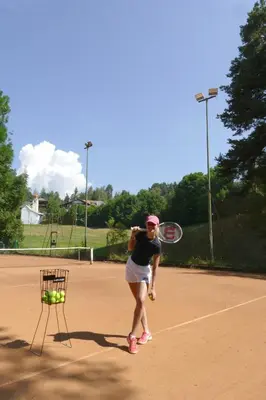 a woman holding a tennis racket on a tennis court at Villa Maier B&B & Apartments in Soprabolzano