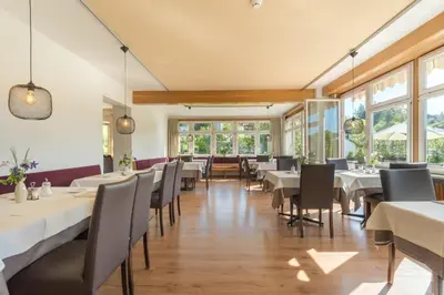 a restaurant with white tables and chairs and windows at Villa Maier B&B & Apartments in Soprabolzano