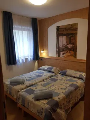 a bedroom with two beds and a large mirror at Casa Alice 5.5 in Fiera di Primiero