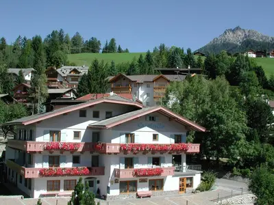 a white apartment building with red balconies in a village at Garni Cristallo in San Vigilio Di Marebbe