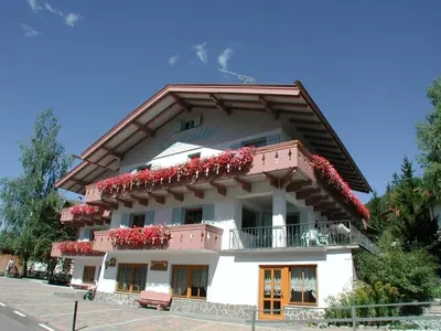 a white building with red flowers on the balcony at Garni Cristallo in San Vigilio Di Marebbe