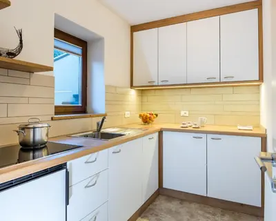 a kitchen with white cabinets and a sink at Apartments Elise in Selva di Val Gardena