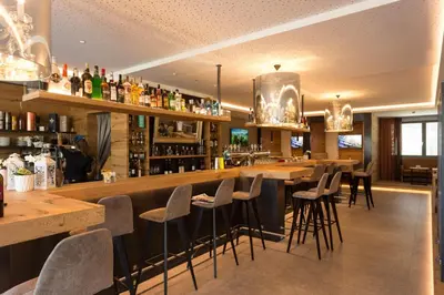 a bar in a restaurant with bar stools at The Lodge Sporthotel - Golfclub Eppan in Appiano sulla Strada del Vino