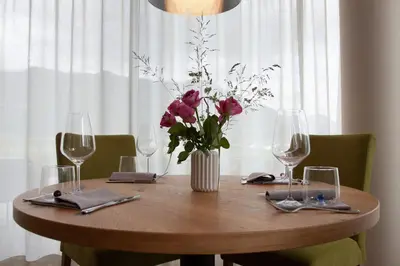 a wooden table with a vase of flowers and wine glasses at The Lodge Sporthotel - Golfclub Eppan in Appiano sulla Strada del Vino