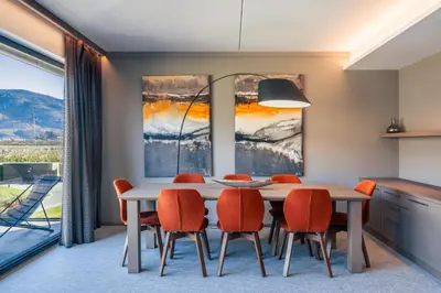 a dining room with a white table and orange chairs at The Lodge Sporthotel - Golfclub Eppan in Appiano sulla Strada del Vino