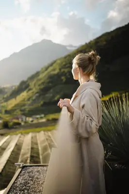 a woman standing on top of a building looking at a mountain at Nutzhof - Mediterran Flair Hotel in Lagundo