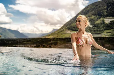 a woman in a bikini standing in the water at Nutzhof - Mediterran Flair Hotel in Lagundo