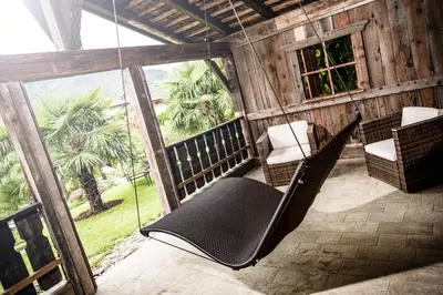 a screened in porch with chairs and a swing at Nutzhof - Mediterran Flair Hotel in Lagundo
