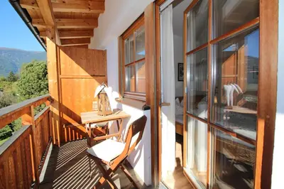 a balcony of a house with a table and a chair at Apartments Im Winkl in Brunico