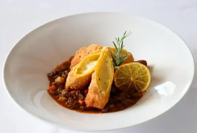 a white plate of food with a bowl of stew at Hotel Oberwirt in Verano