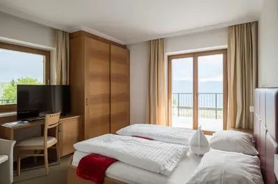 a hotel room with two beds and a desk and a television at Hotel Oberwirt in Verano