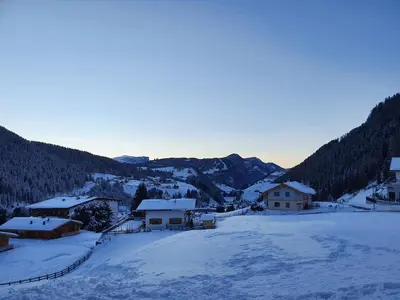 a village covered in snow with mountains in the background at Appartamento Dolomiti in Selva di Val Gardena