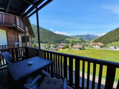 a balcony with a table and chairs and mountains at Appartamento Dolomiti in Selva di Val Gardena