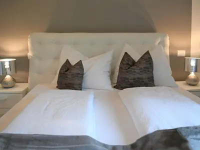 a white bed with two pillows and two lamps at Appartamento Dolomiti in Selva di Val Gardena
