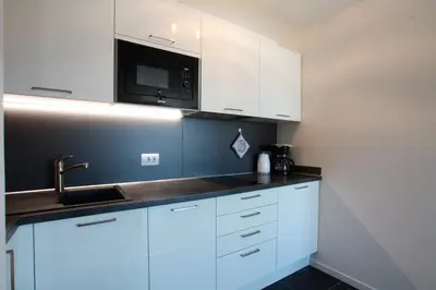 a kitchen with white cabinets and a microwave at Appartamento Dolomiti in Selva di Val Gardena