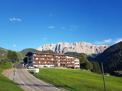 a building on the side of a road with a mountain at Appartamento Dolomiti in Selva di Val Gardena