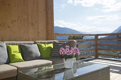 a patio with a couch and a glass table with flowers at Berg-Weiler-Obereggerhof in Schenna