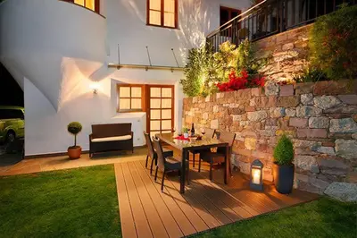 a patio with a table and chairs and a stone wall at Berg-Weiler-Obereggerhof in Schenna