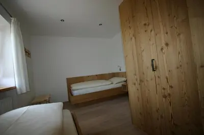 a small bedroom with a bed and a wooden door at Hilpoldhof in Castelrotto