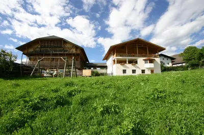 two barns on a hill with a green field at Hilpoldhof in Castelrotto