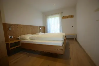 a large bed in a room with a window at Hilpoldhof in Castelrotto