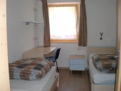a small room with two beds and a window at Anna Apartment in Pozza di Fassa