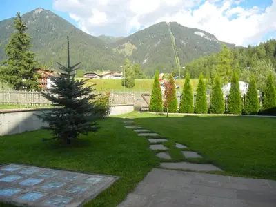 a garden with a christmas tree in the grass at Anna Apartment in Pozza di Fassa