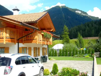 a white car parked in front of a house at Anna Apartment in Pozza di Fassa