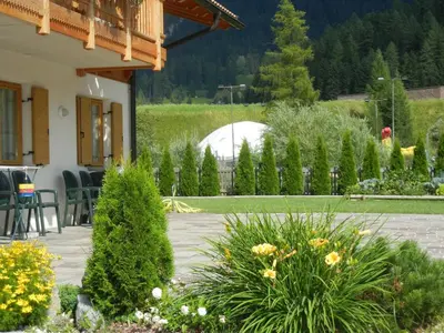 a patio with a garden with trees and plants at Anna Apartment in Pozza di Fassa