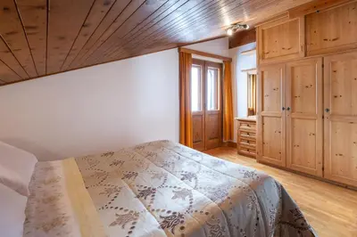a bedroom with a bed and a wooden ceiling at ATTICO Lodge in Cortina dʼAmpezzo