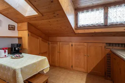 a kitchen with wooden cabinets and a table with a coffee maker at ATTICO Lodge in Cortina dʼAmpezzo