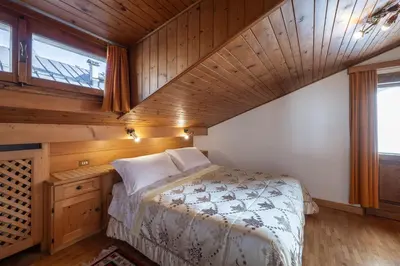 a bedroom with a bed and a wooden ceiling at ATTICO Lodge in Cortina dʼAmpezzo
