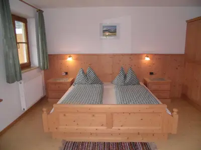 a bedroom with a wooden bed with blue pillows at Appartements Färberhof in Valdaora
