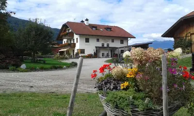 a green field with a town and mountains in the background at Appartements Färberhof in Valdaora