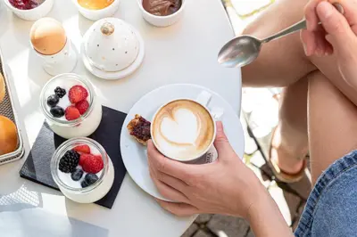 a person holding a cup of coffee on a table with fruit at Alter Schlachthof in Bressanone