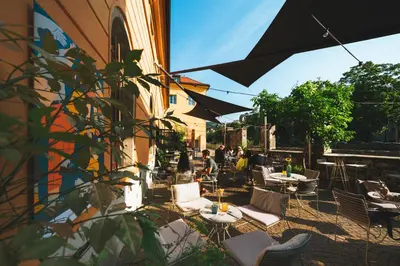 an outdoor patio with tables and chairs and people sitting at Alter Schlachthof in Bressanone